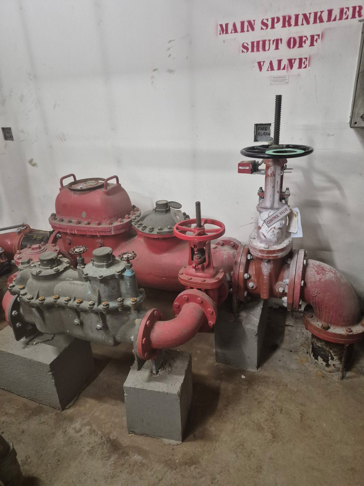 Main sprinkler shut-off valve and backflow preventer set on housekeeping blocks
